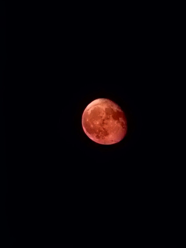 A blood moon during a lunar eclipse with a reddish hue in the night sky.