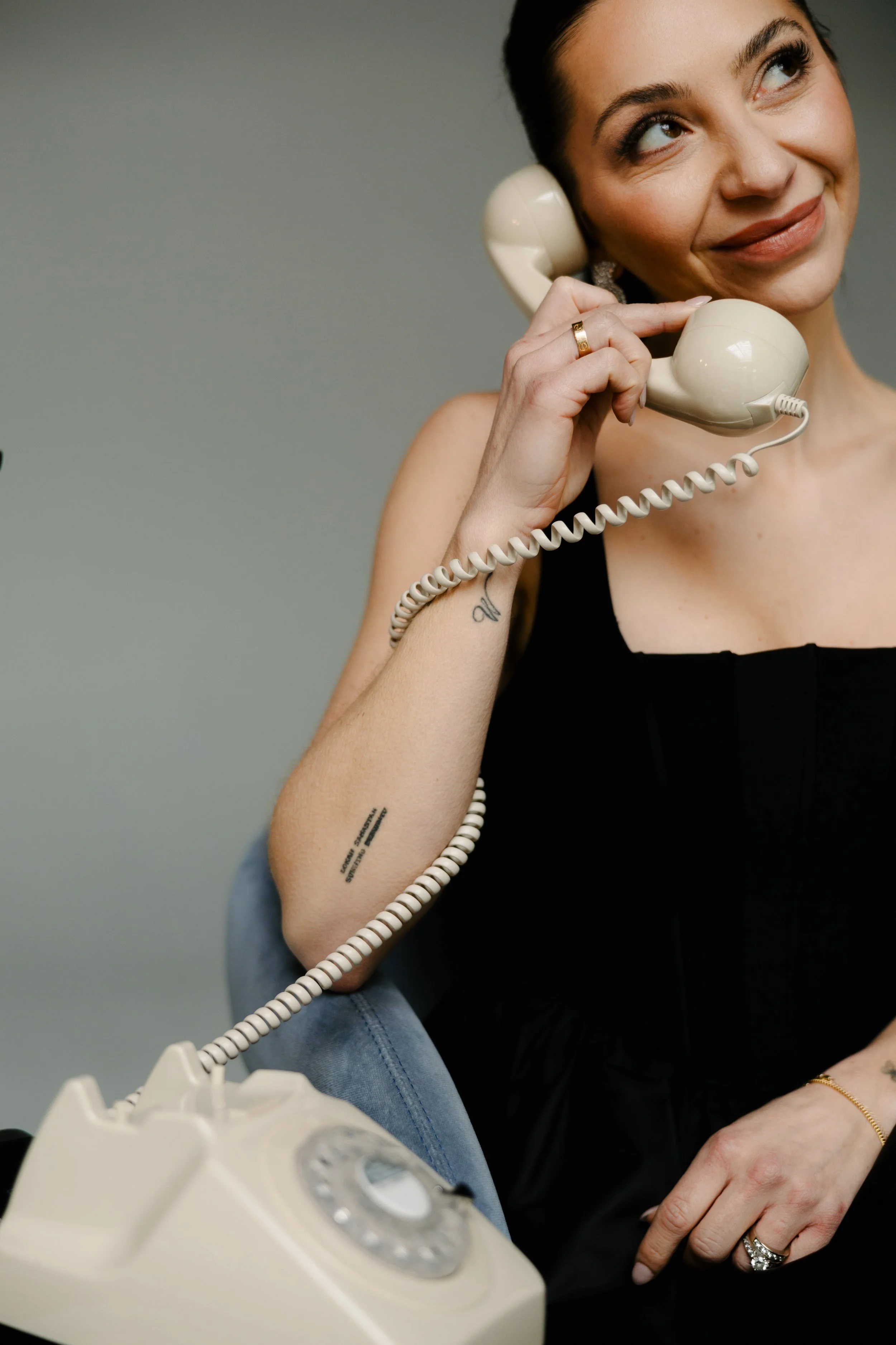 image of a woman in an elegant little black dress sitting on a chair talking on the phone