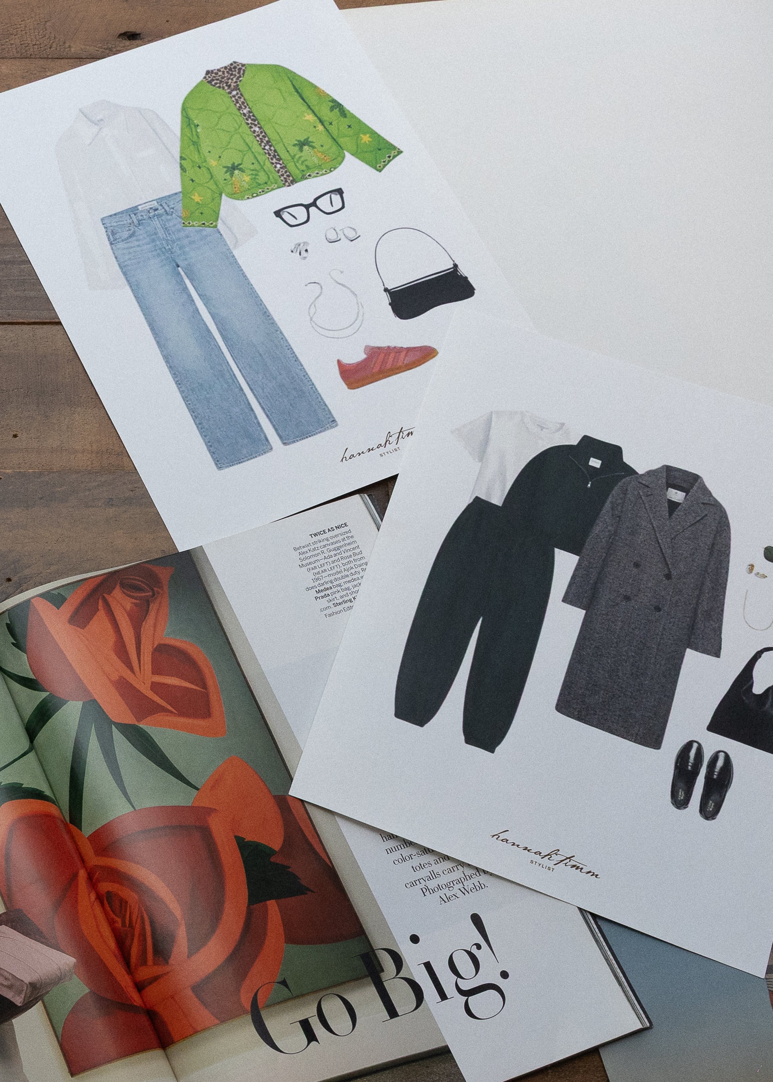 Clothing and fashion illustrations on paper, including a green jacket, blue jeans, black dress, gray coat, sunglasses, and shoes, laid out on a table.