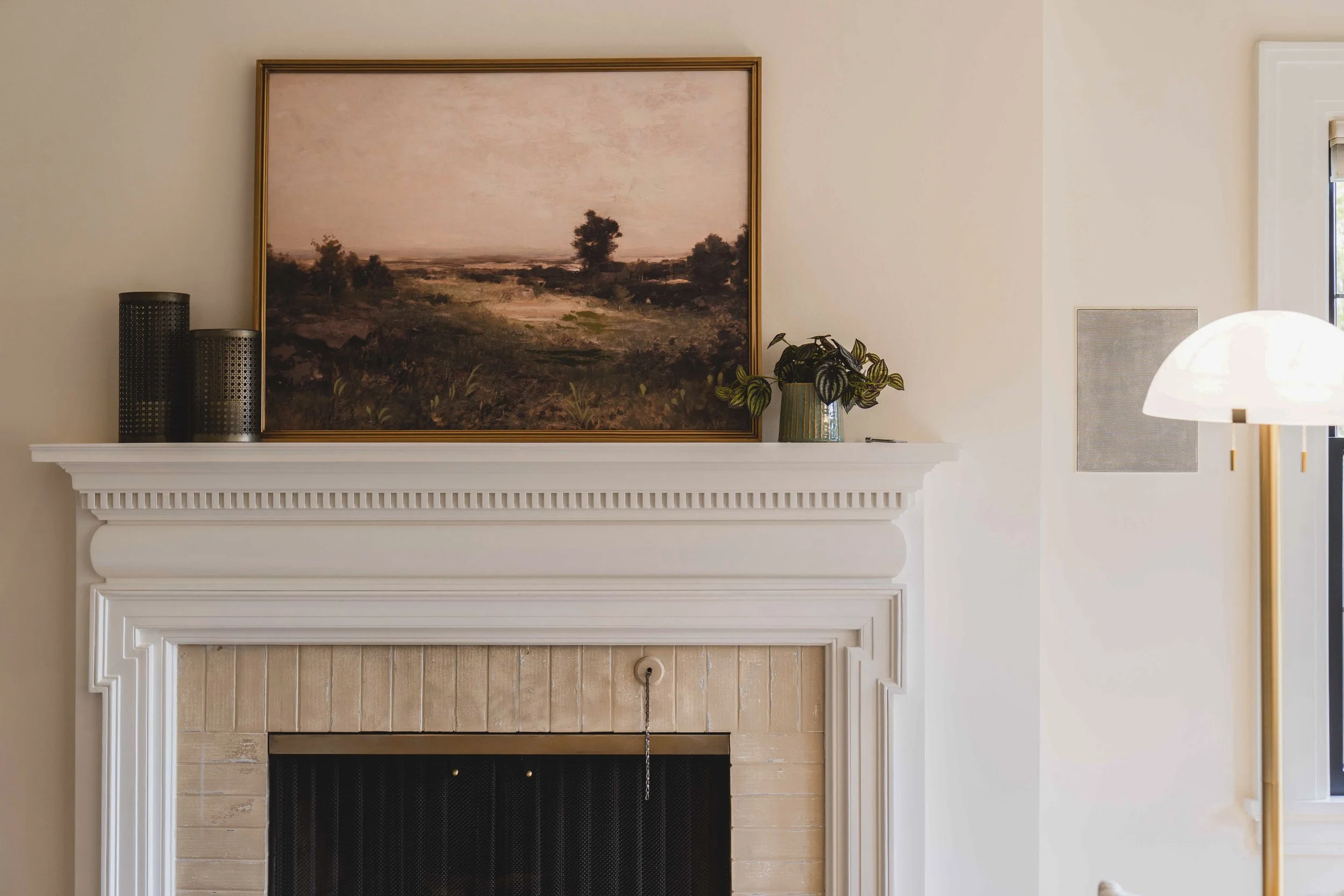 Front view of a two-story house with white brick exterior, brown shutters, landscaped garden, and a sidewalk leading to the front door under a clear blue sky.