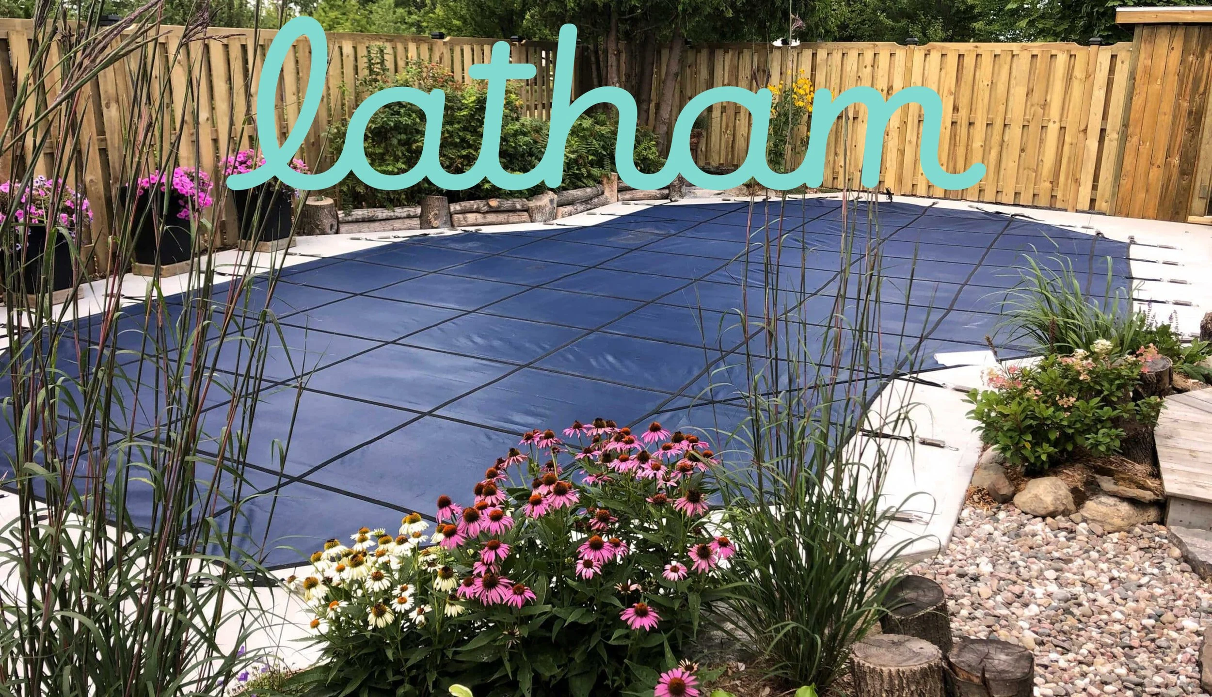 Backyard with a swimming pool covered by a blue safety cover, surrounded by a wooden fence, potted flowers, and garden plants, with the word 'Latham' written across the top in light blue script.
