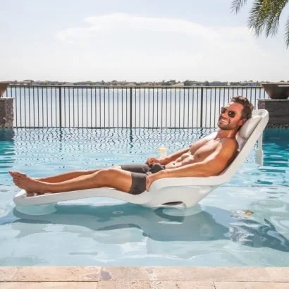 Man relaxing on a pool float in a rooftop swimming pool with city view.