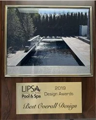 A framed award plaque for best overall design at the 2019 LIPSA Pool & Spa Design Awards, featuring a photograph of a modern outdoor pool with surrounding trees.