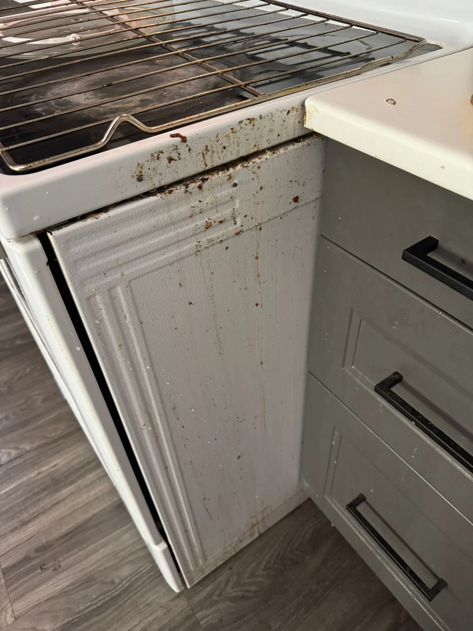 Close-up of an old, dirty kitchen stove with rust and stains on the surface and side panel.