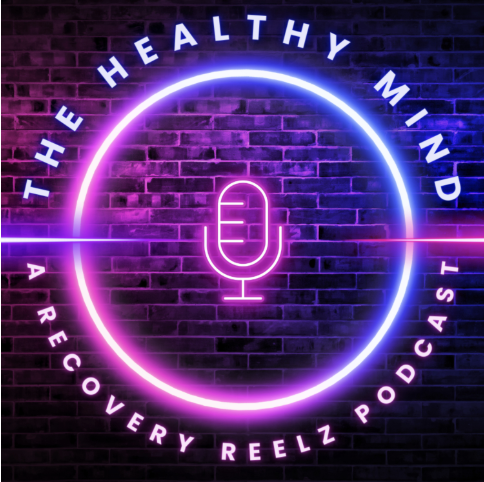 Neon sign with a microphone inside a circle, surrounded by the text "The Healthy Mind" and "A Recovery Reelz Podcast" on a brick wall background.
