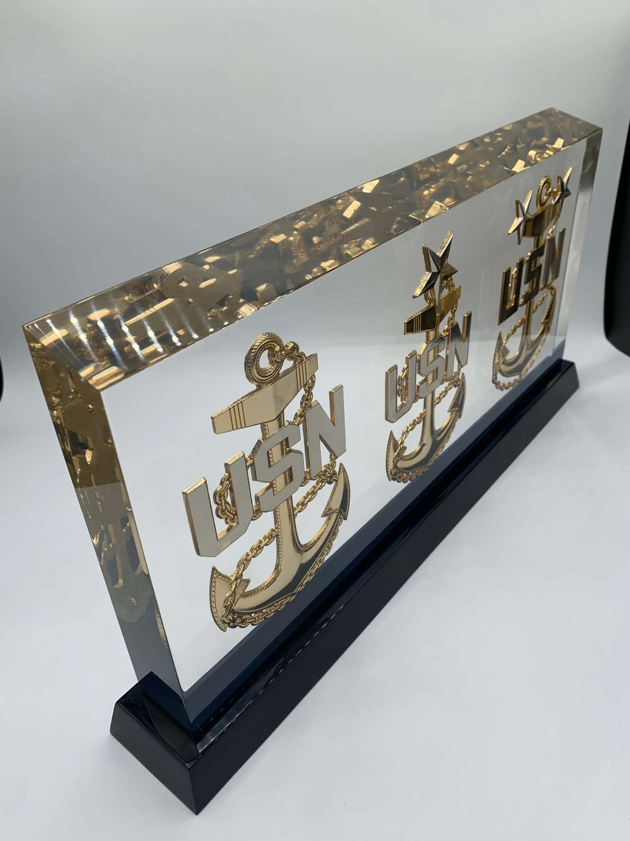 Decorative art piece with gold sailboats, words 'LISN' and 'LISEN', and stars, mounted on a black base.