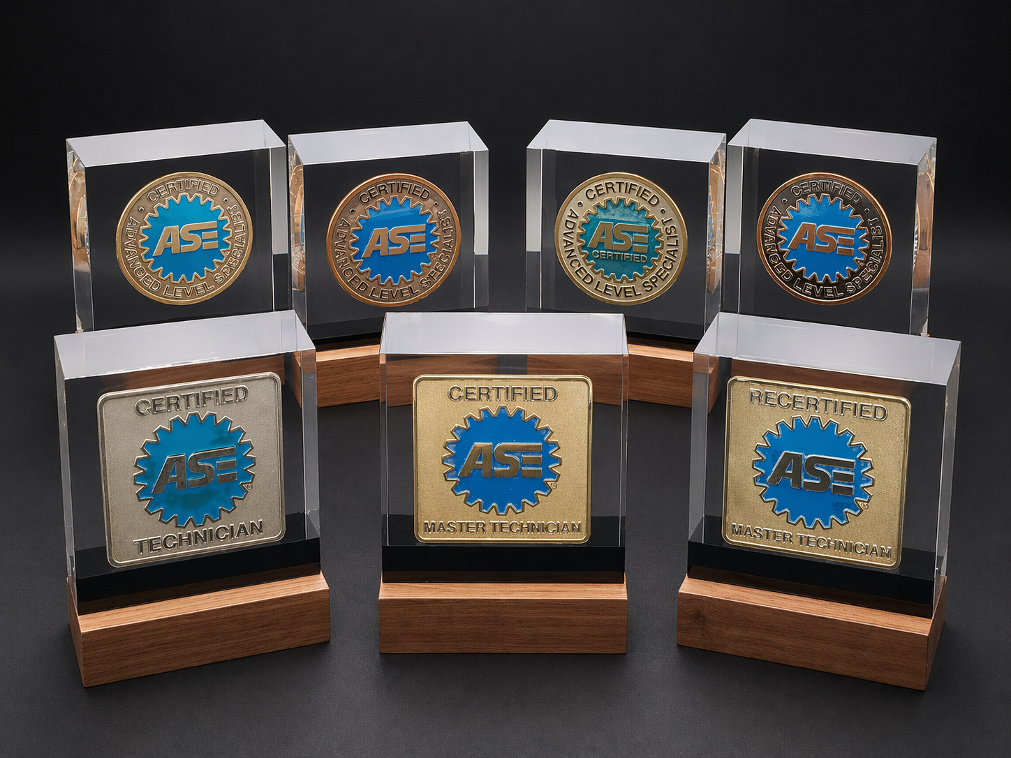 Collection of seven ASE certification plaques, including certified, certified advanced level specialist, certified technician, master technician, and recertified master technician, displayed on wooden bases against a black background.