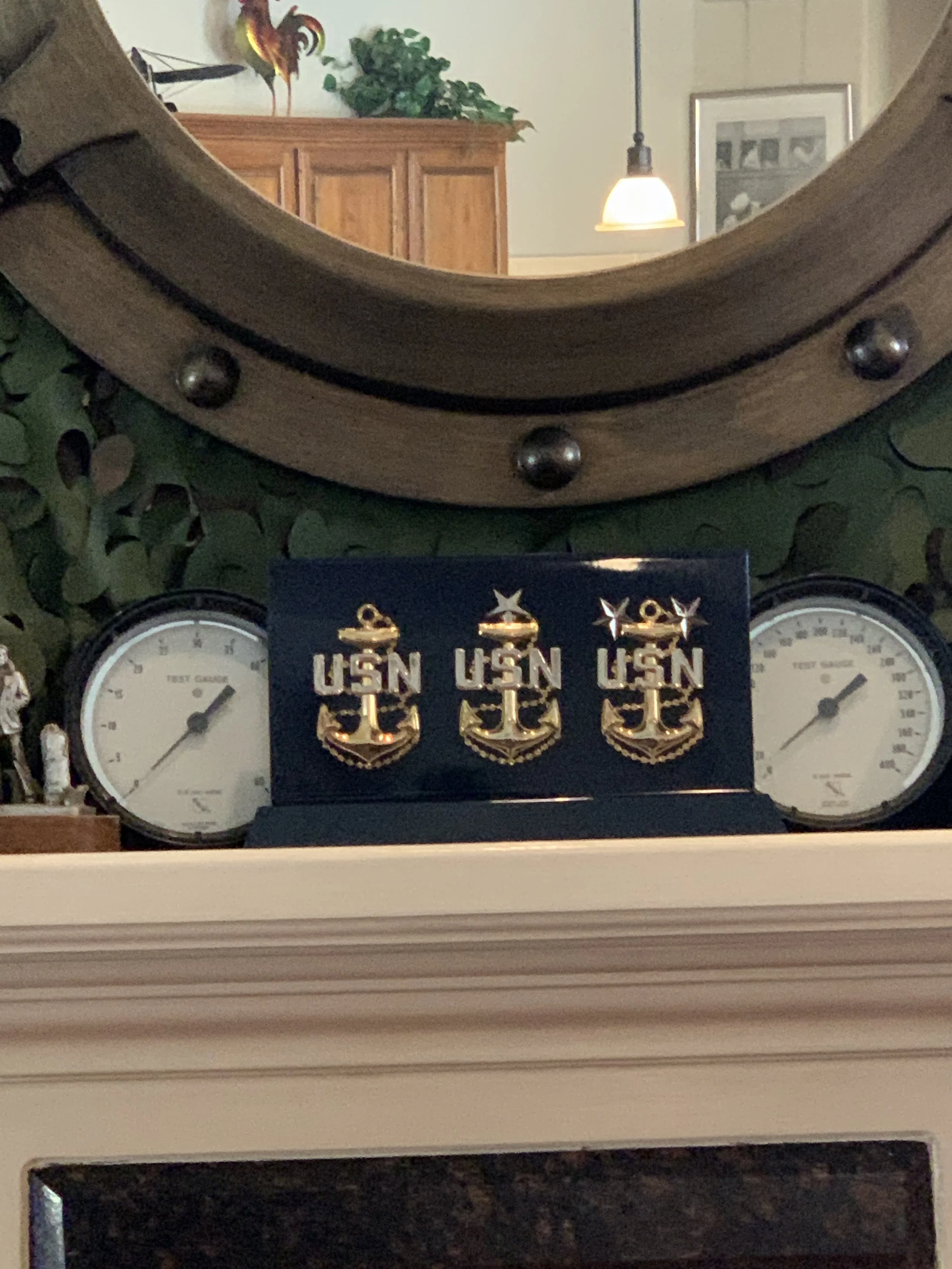 Decorative display featuring three gold and navy United States Navy (USN) anchor insignias, flanked by two analog gauges labeled 'Test Gauge' and 'Vees Gauge' on a white fireplace mantel.