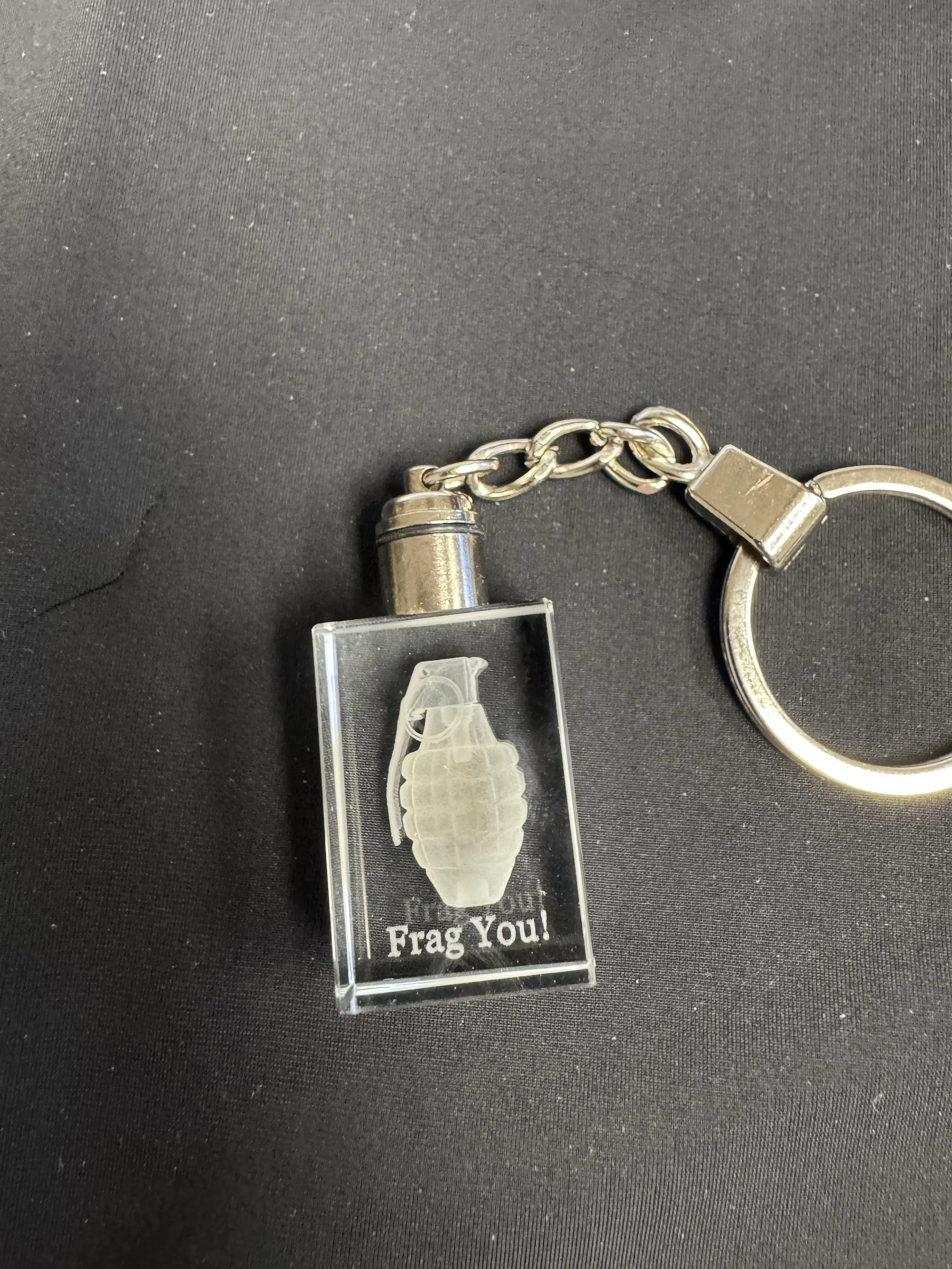 Keychain with a rectangular acrylic charm featuring a white illustration of a grenade and the words "Frag You!" on a black background.
