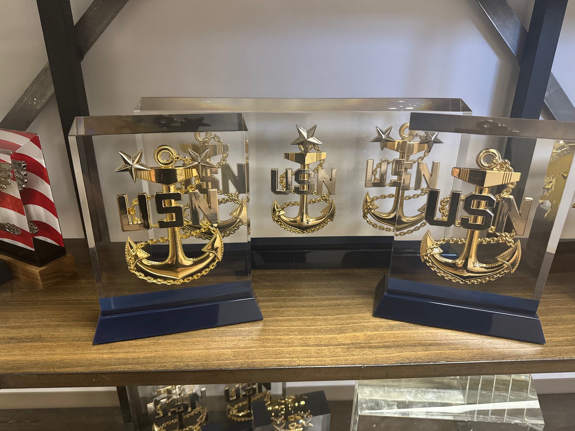 Decorative trophies with naval anchors, stars, and the text 'USN' in gold, displayed on a wooden surface.