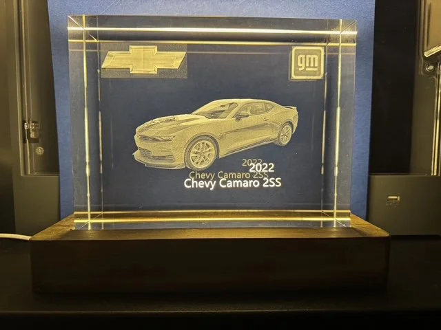 A clear illuminated acrylic display case with a 3D laser-etched image of a 2022 Chevrolet Camaro SS, Chevrolet logo, GM logo, and text indicating the model year.