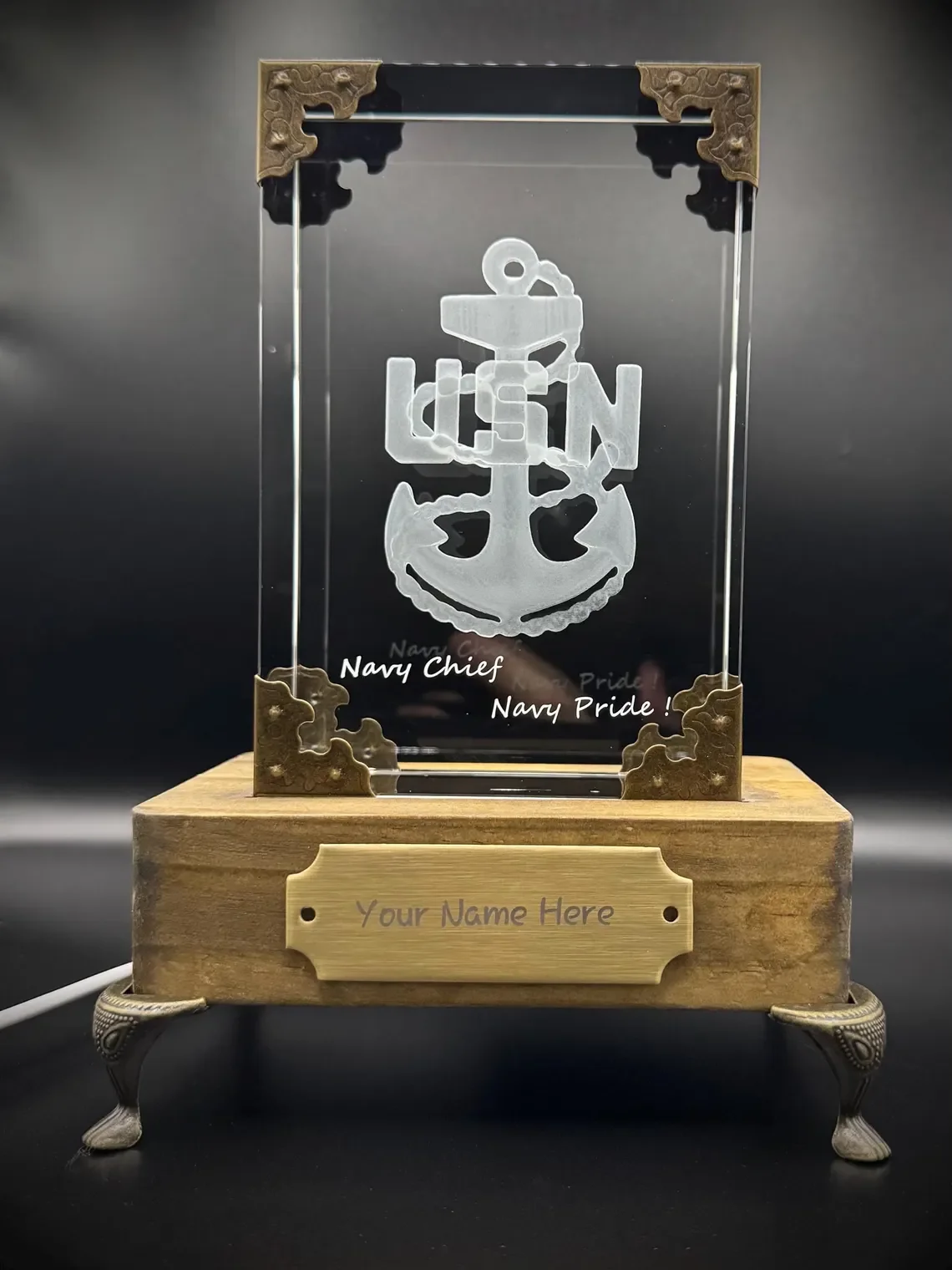 A glass award with a naval emblem featuring an anchor and the acronym 'USN', mounted on a wooden base with a customizable nameplate. The award is engraved with 'Navy Chief' and 'Navy Pride!'