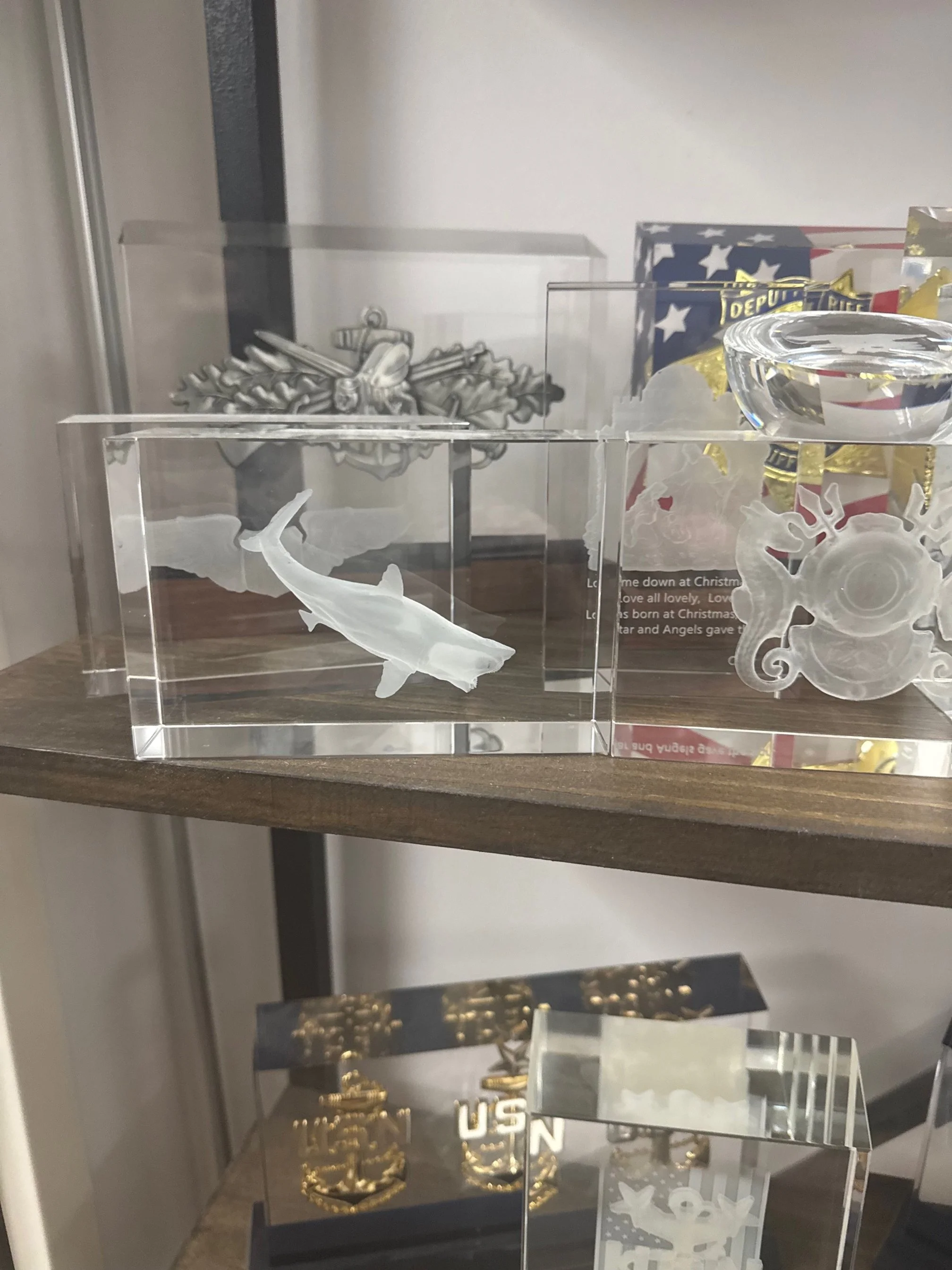 Decorative glass ornaments and figurines, some featuring patriotic and military themes, displayed on a wooden surface.