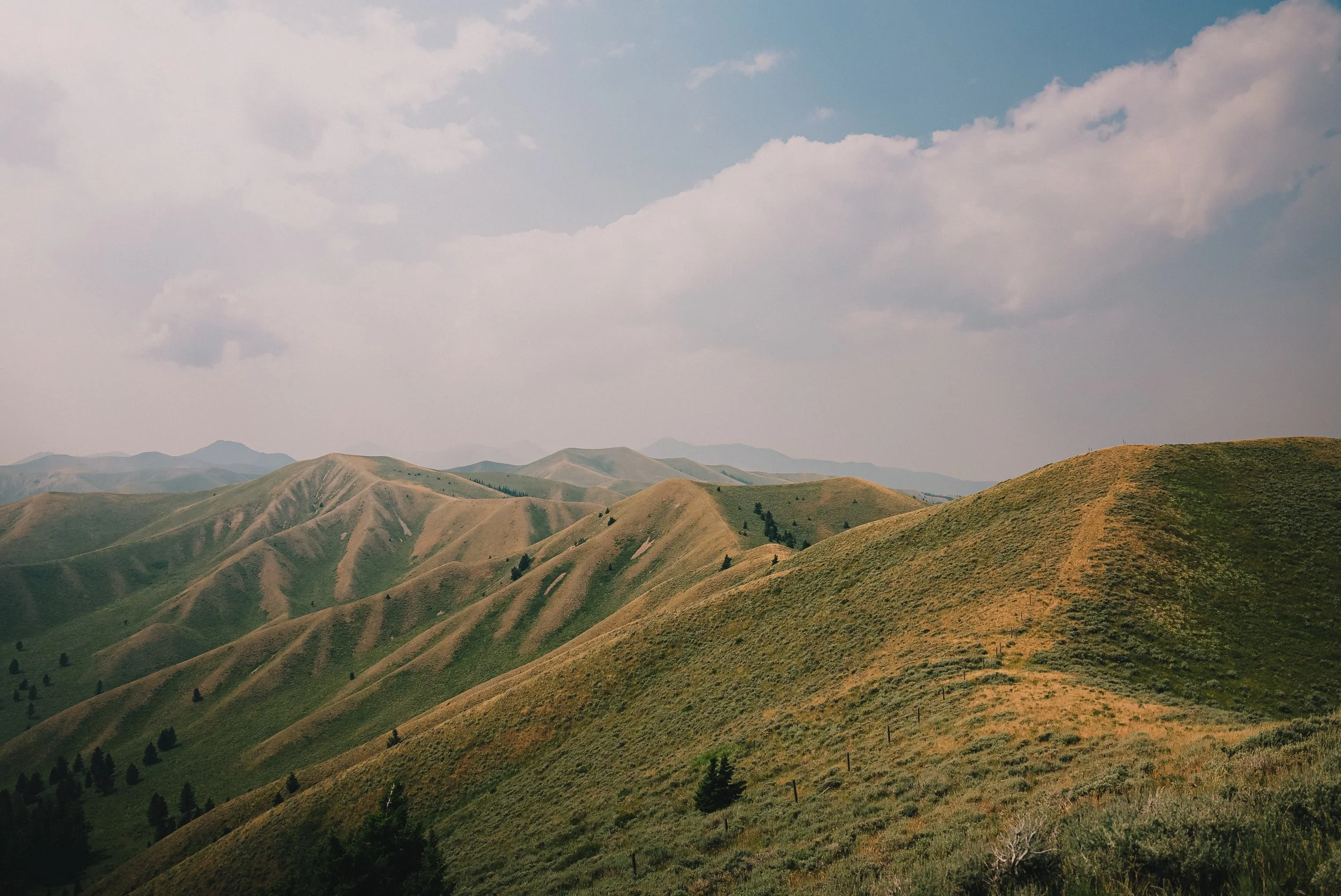 Rolling green hills under a partly cloudy sky.
