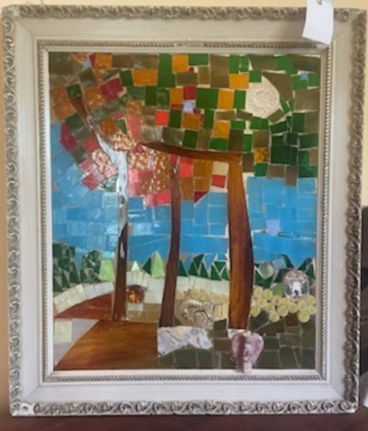 Mosaic art of a landscape with two trees, a bridge, a lake, and flowers, framed in an ornate white border.