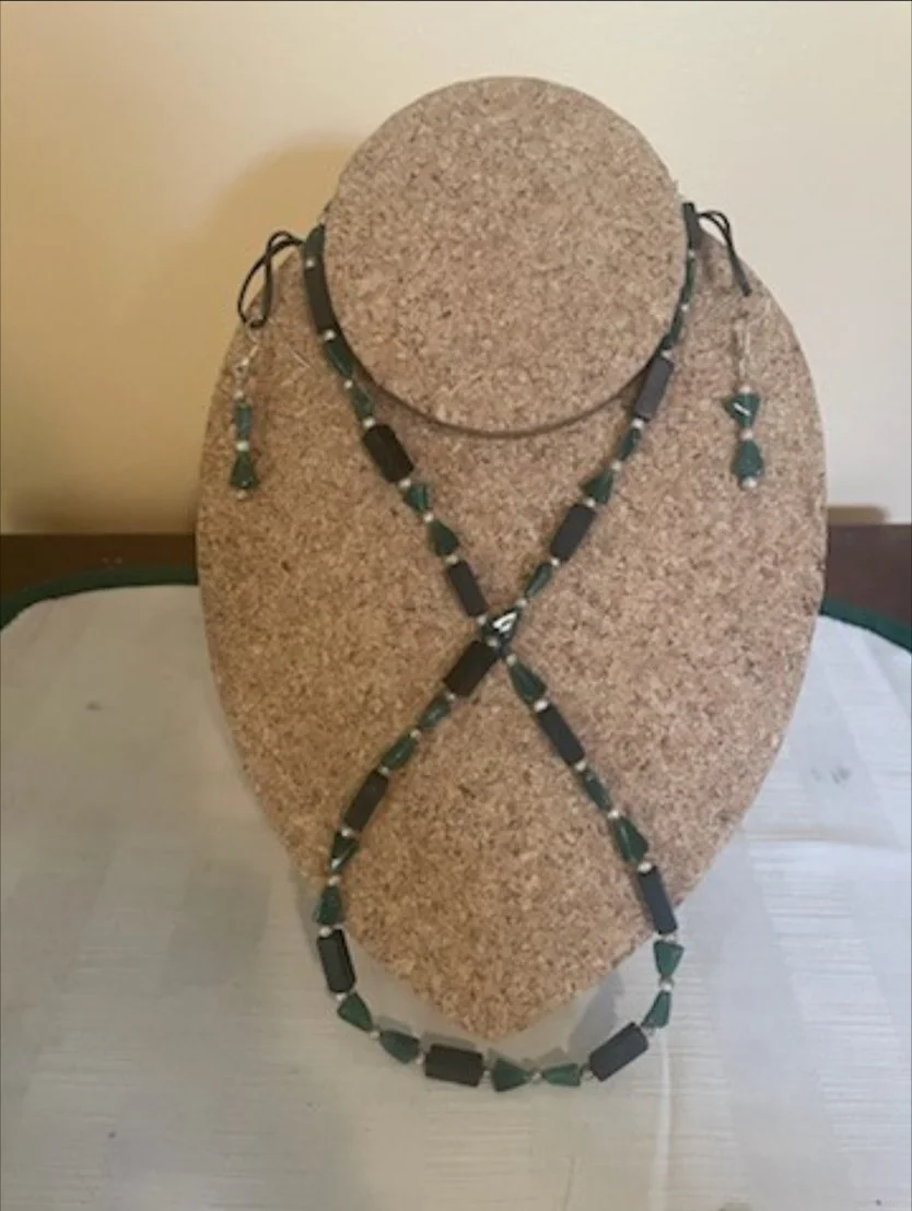 Jewelry display with a necklace and earrings on a cork bust.