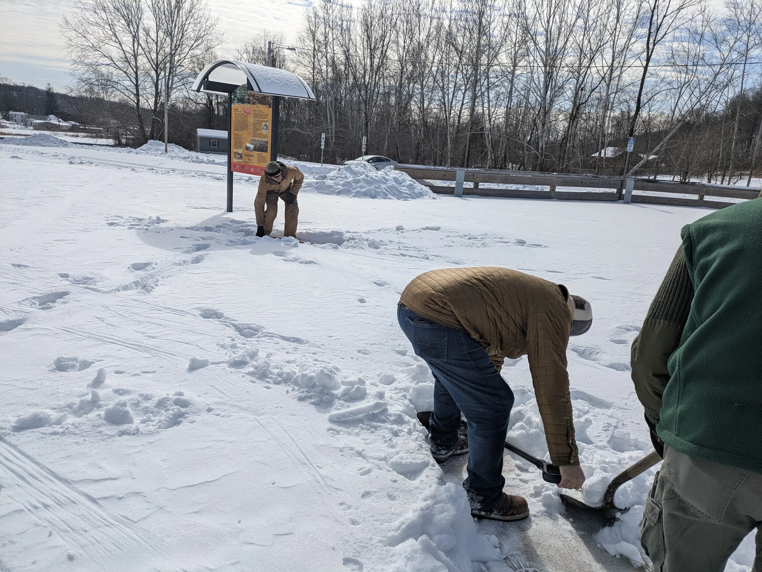People shoveling snow in a parking lot.