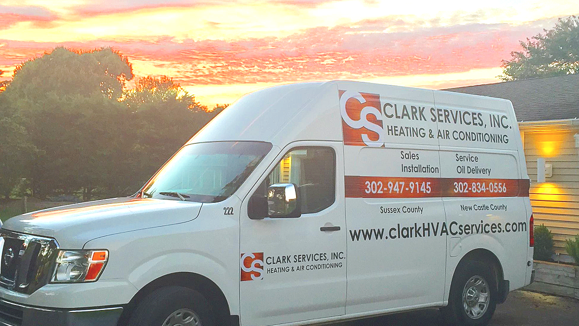 White van with Clark Services, Inc. heating and air conditioning branding, parked outside at sunset.