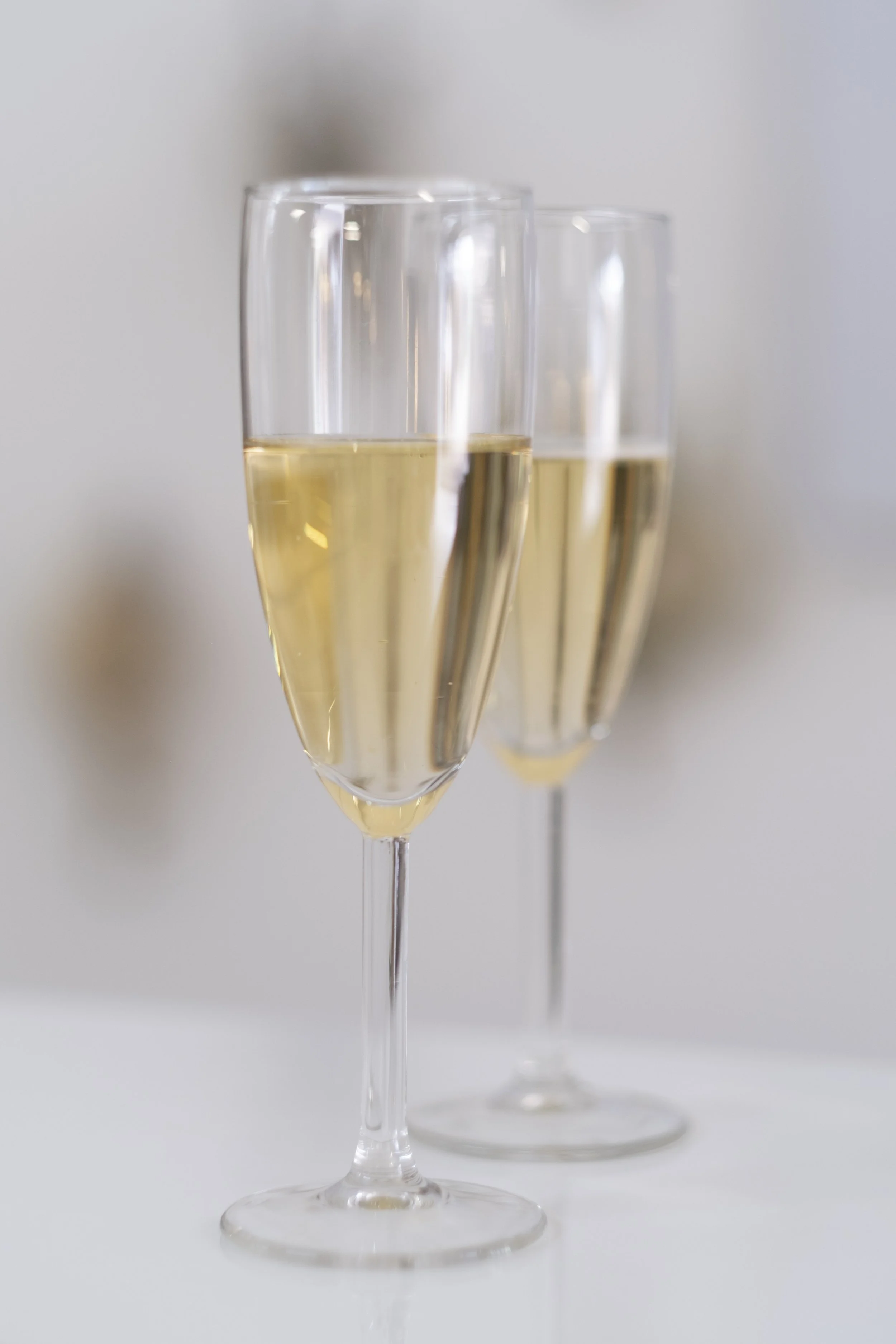 Three champagne flutes filled with sparkling wine on a white surface.