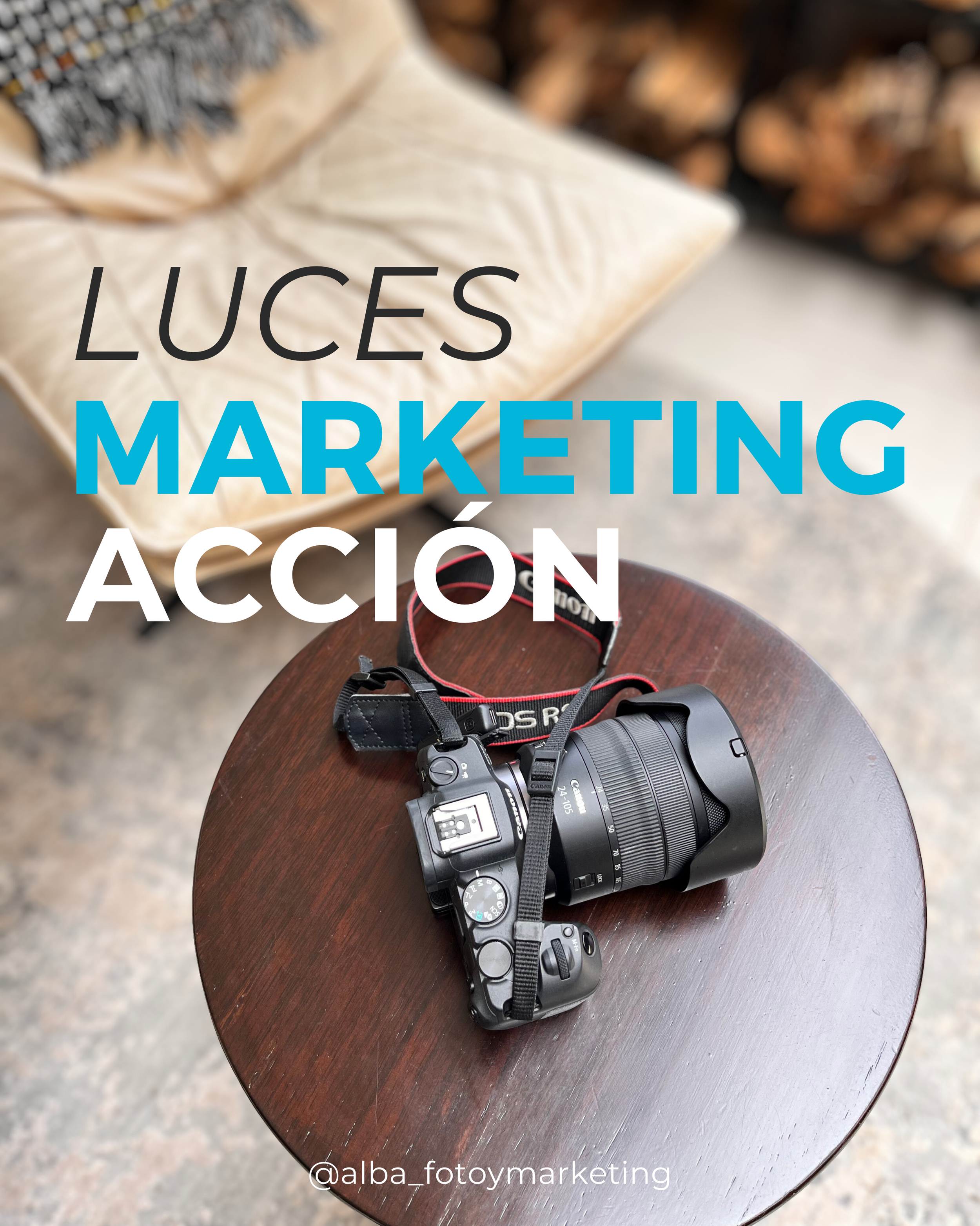 Una cámara digital colocada sobre una mesa redonda de madera. En el fondo, una manta o cojín beige y madera apilada. Texto en la imagen: 'LUZES', 'MARKETING', 'ACCIÓN'.