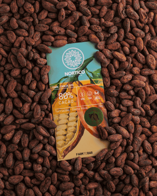 Barra de chocolate oscuro con 80% de cacao rodeada de cacaos secos, con etiqueta que indica origen en Costa Rica y marca NORTICO.