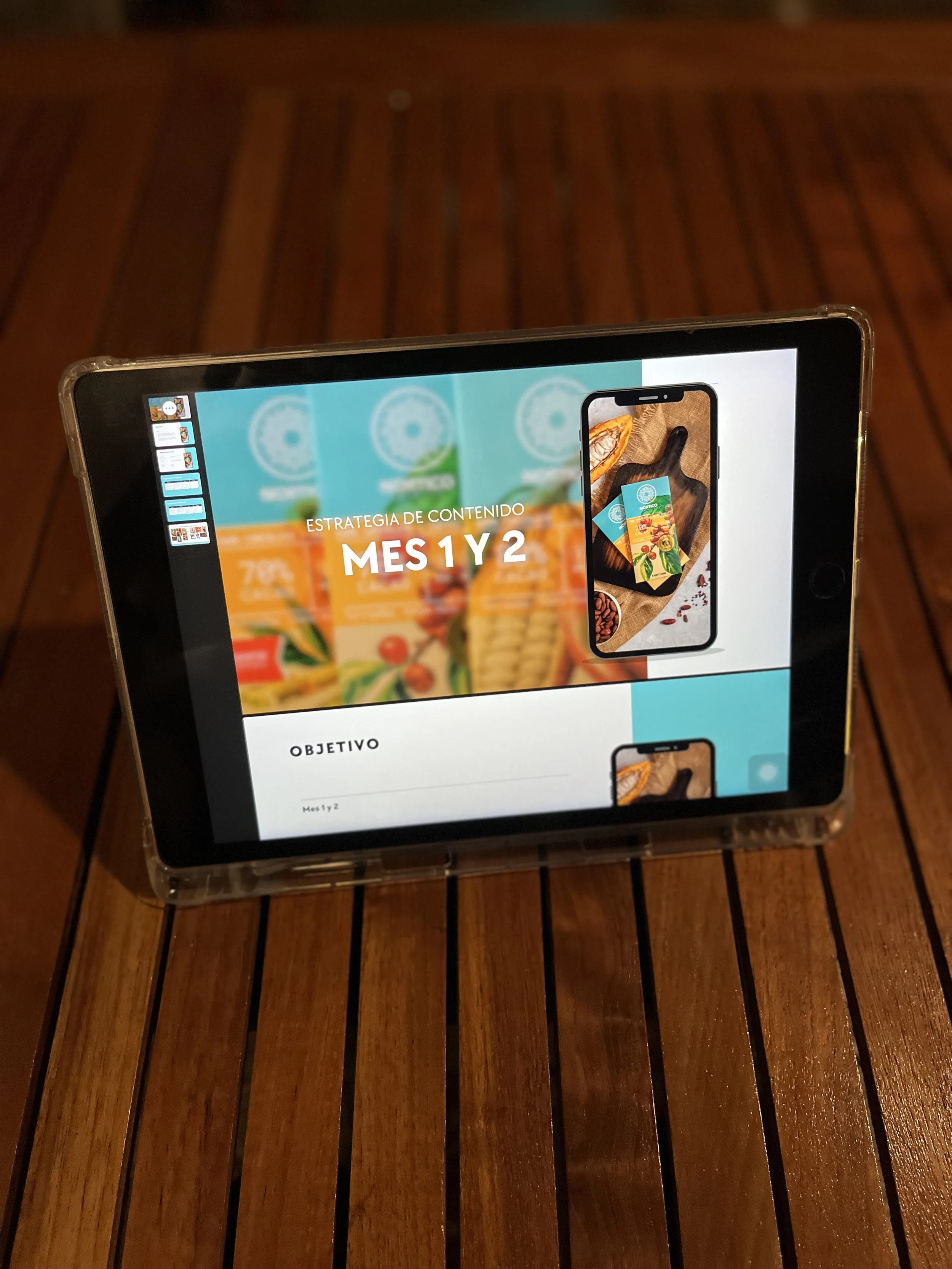 Presentación en una tablet que muestra una estrategia de contenido para los meses 1 y 2, con imágenes de productos alimenticios y un teléfono móvil en la pantalla