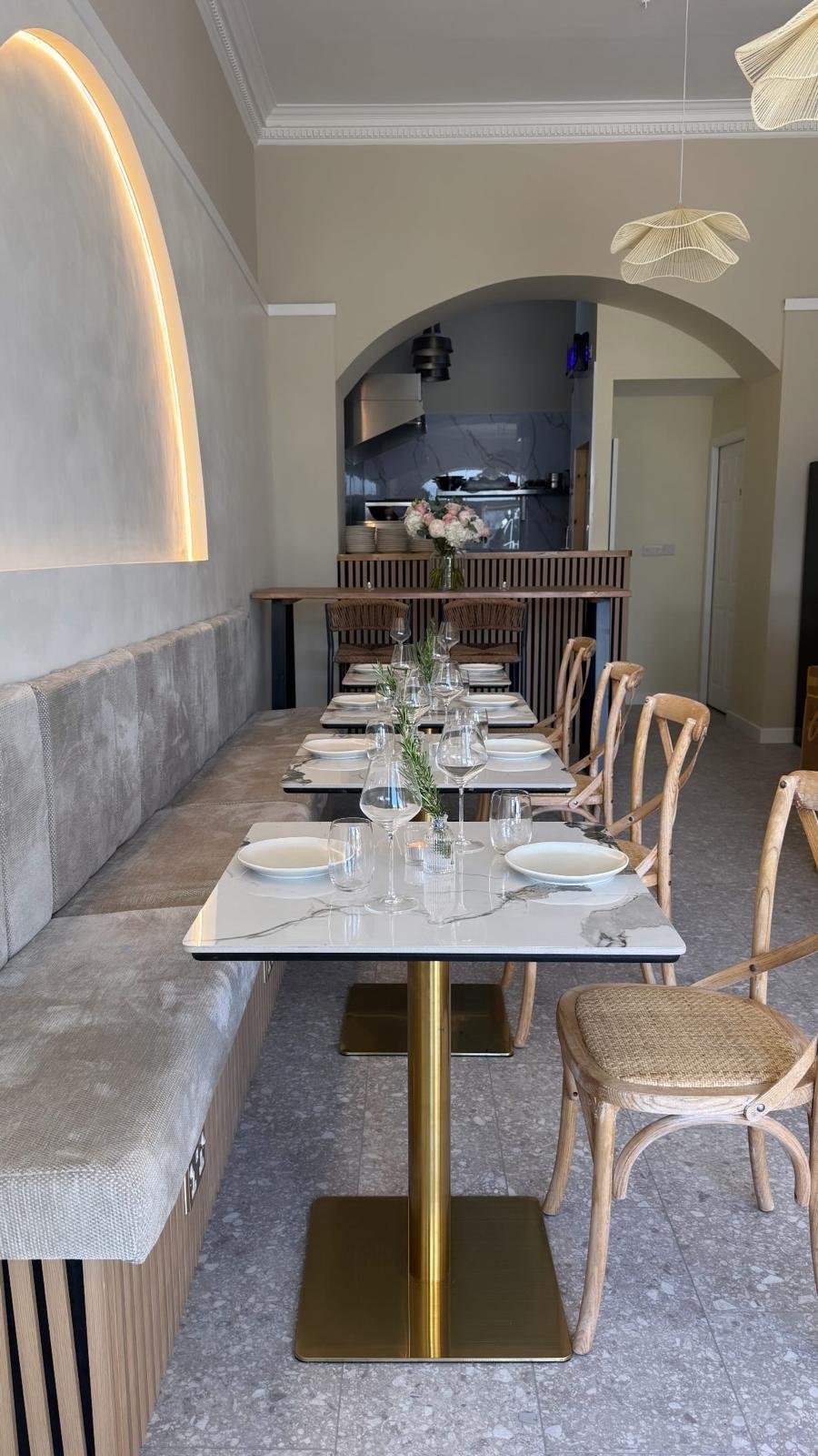 Interior of a modern Mediterranean restaurant with warm lighting and marble tables.