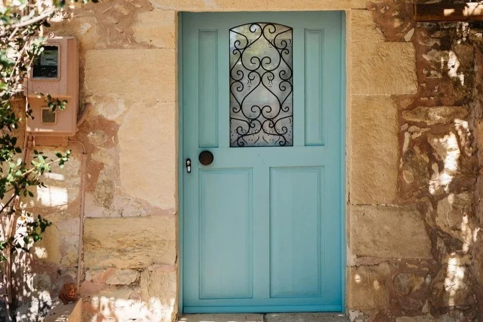 Traditional Mediterranean stone building with a pastel blue doorway.