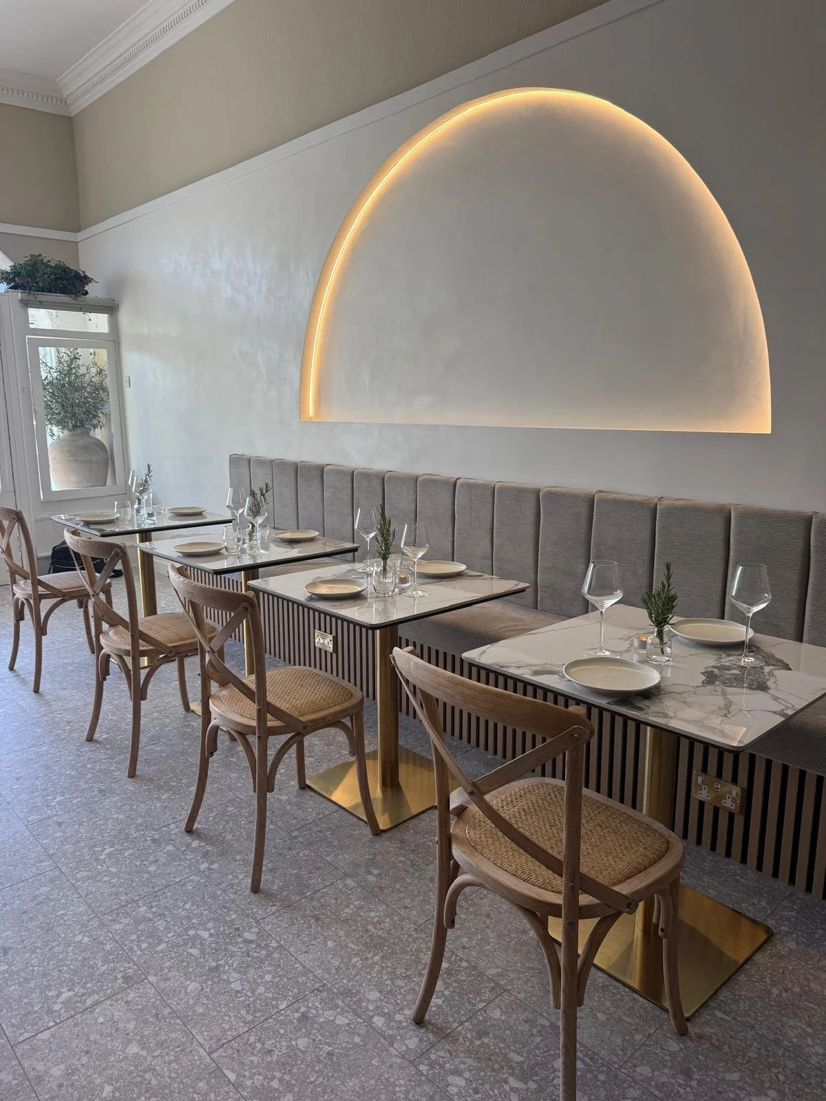 Interior of a modern Mediterranean restaurant with warm lighting and marble tables.