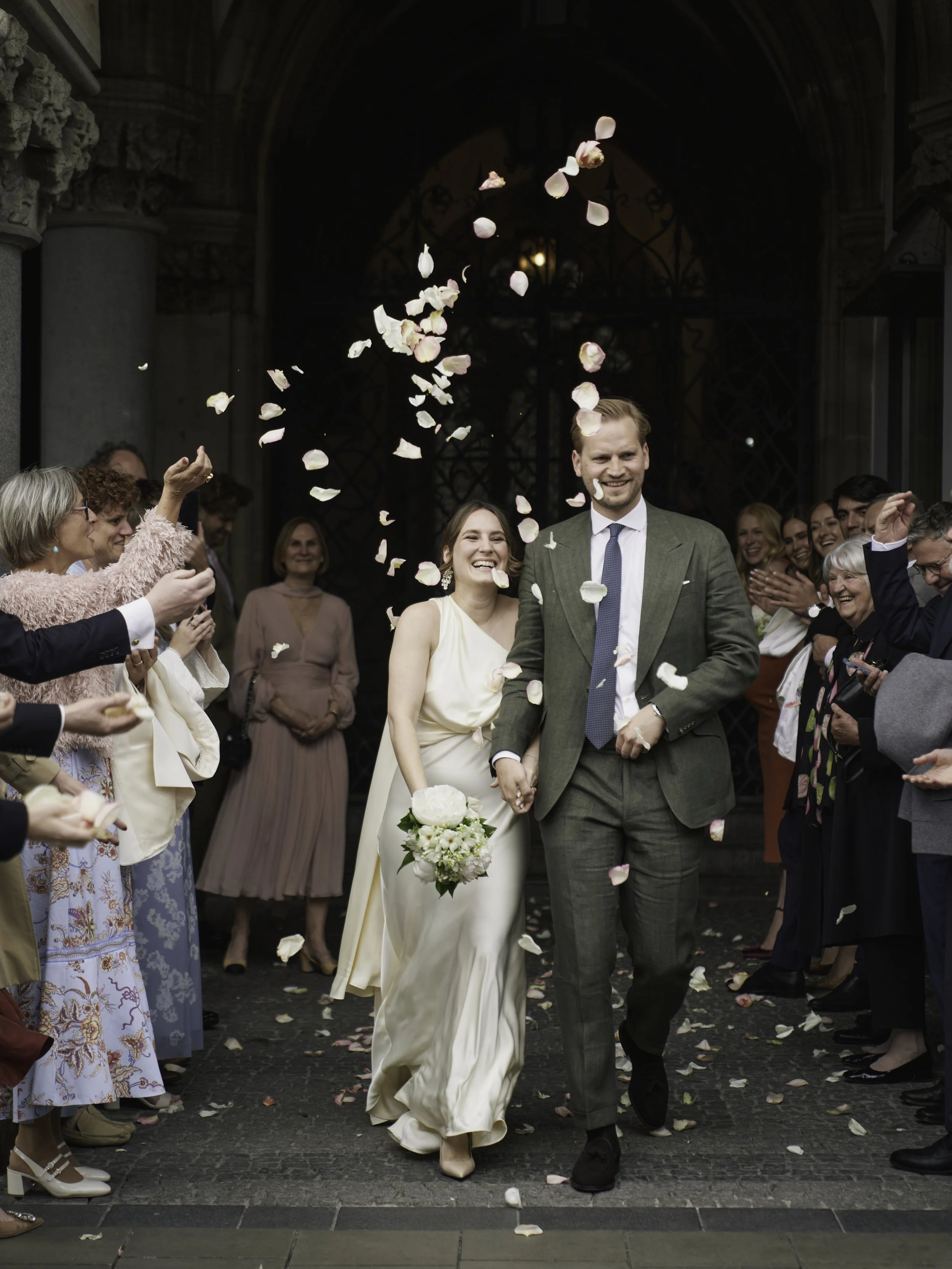 Ein frisch verheiratetes Paar läuft Hand in Hand durch eine Menge von Freunden und Familie, die mit Reis und Blumenblüten werfen.