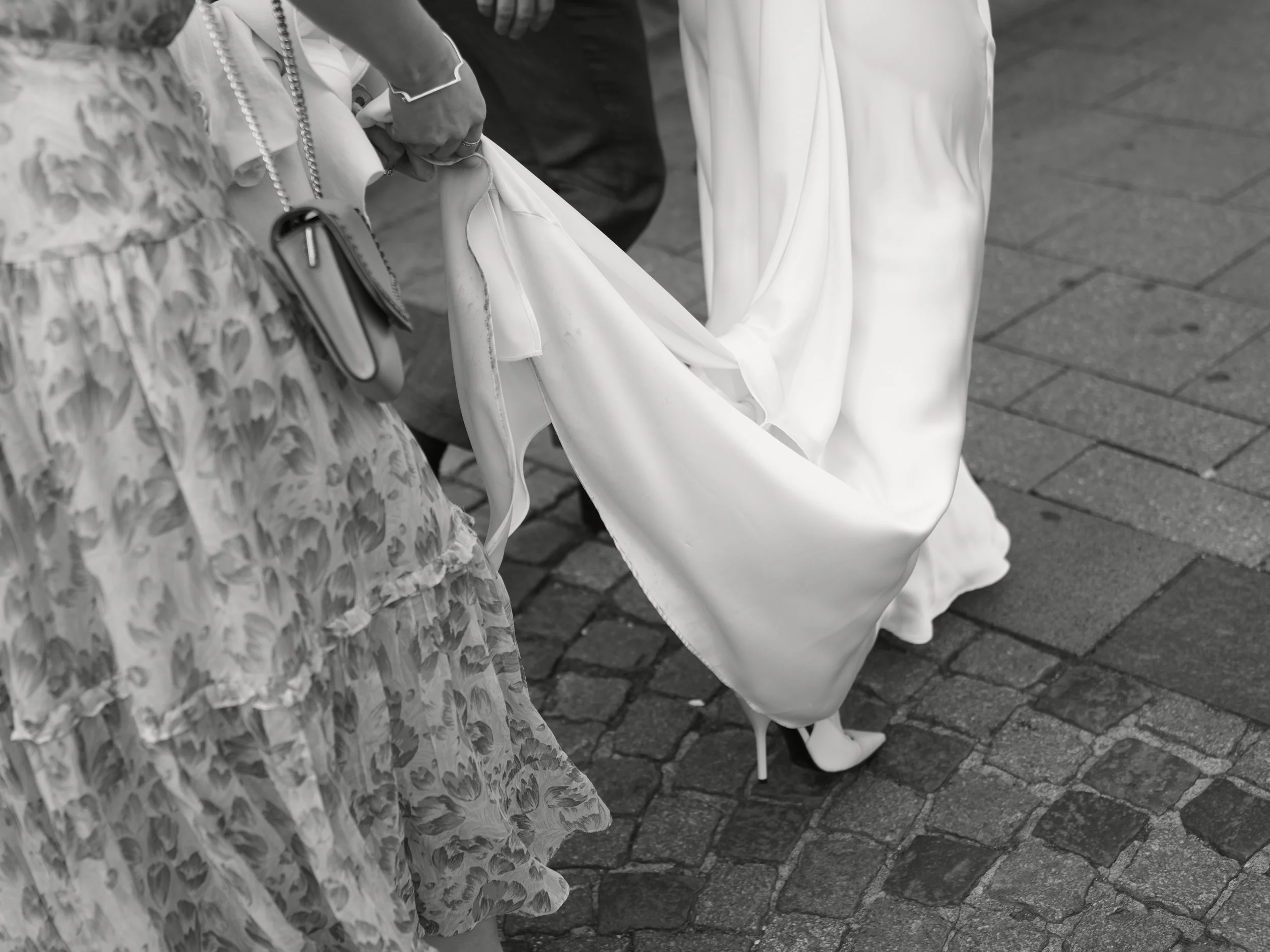 Die Trauzeugin hält das Brautkleid, während sie sich auf dem Weg zur Trauung befinden.