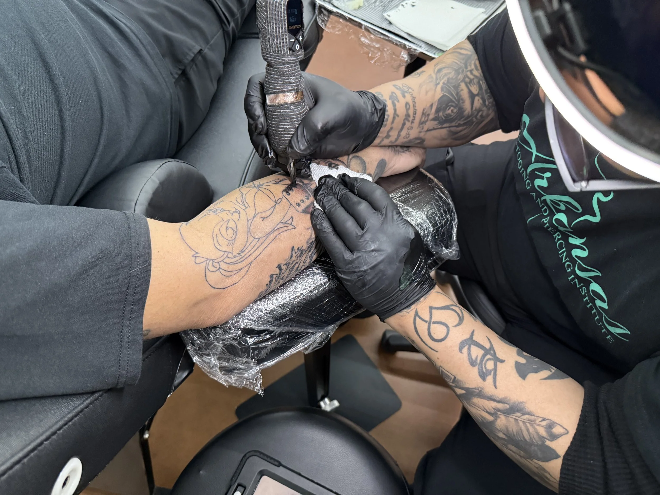 student applying a tattoo on clients forearm.