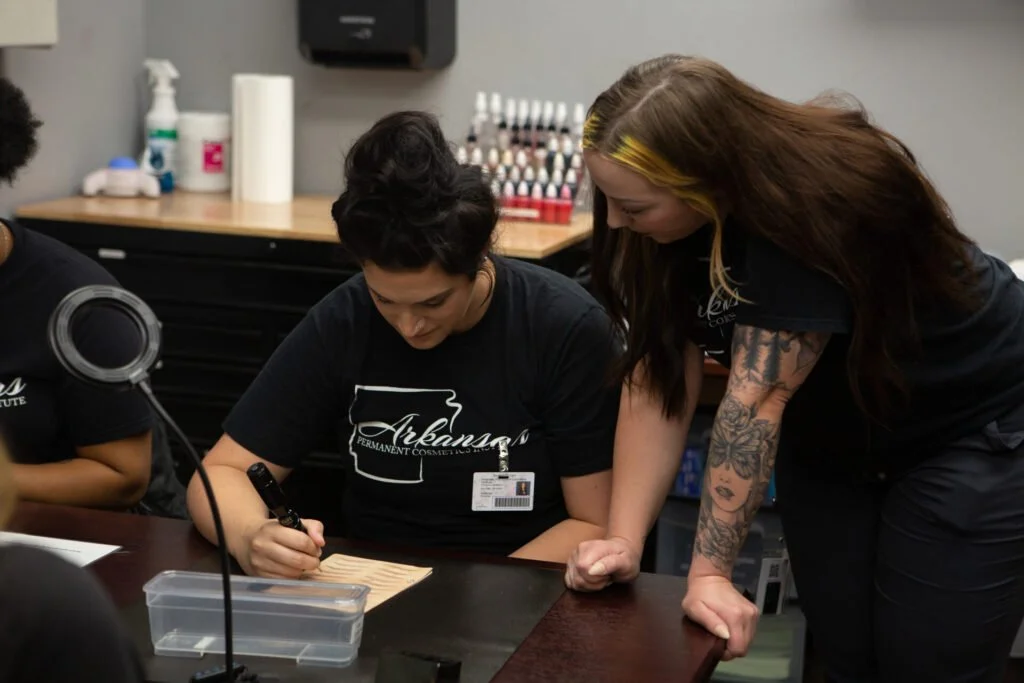Instructor supervising a student practicing pmu techniques