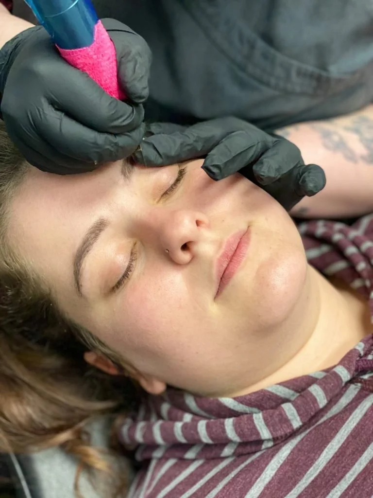 Permanent makeup artist applying eyebrow pigment on a client’s brows