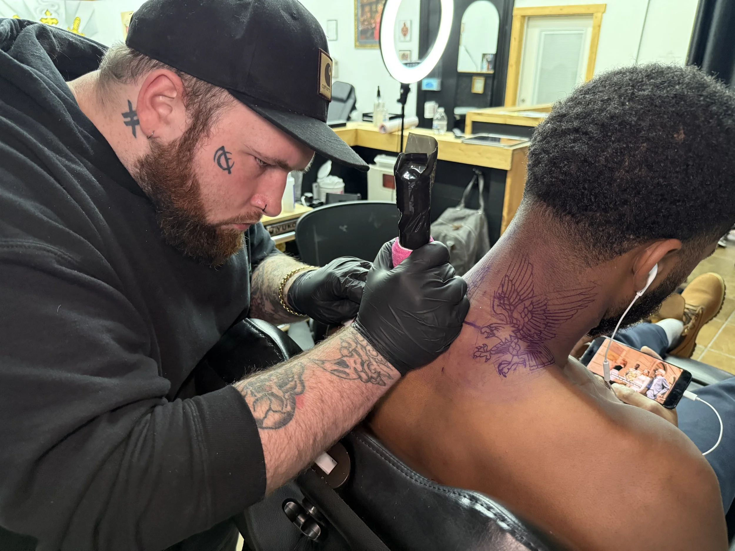 Artist and instructor applying ink to a neck tattoo