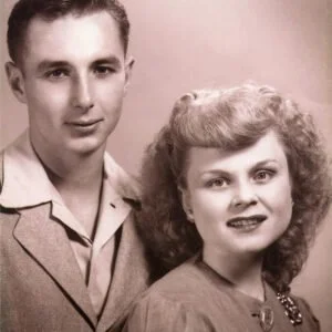 A black-and-white vintage photo of a young man and woman smiling for a portrait.