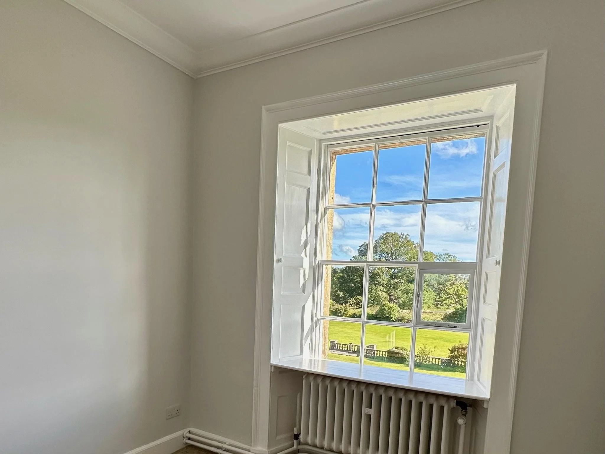 Bright apartment room with traditional sash window and scenic countryside outlook.