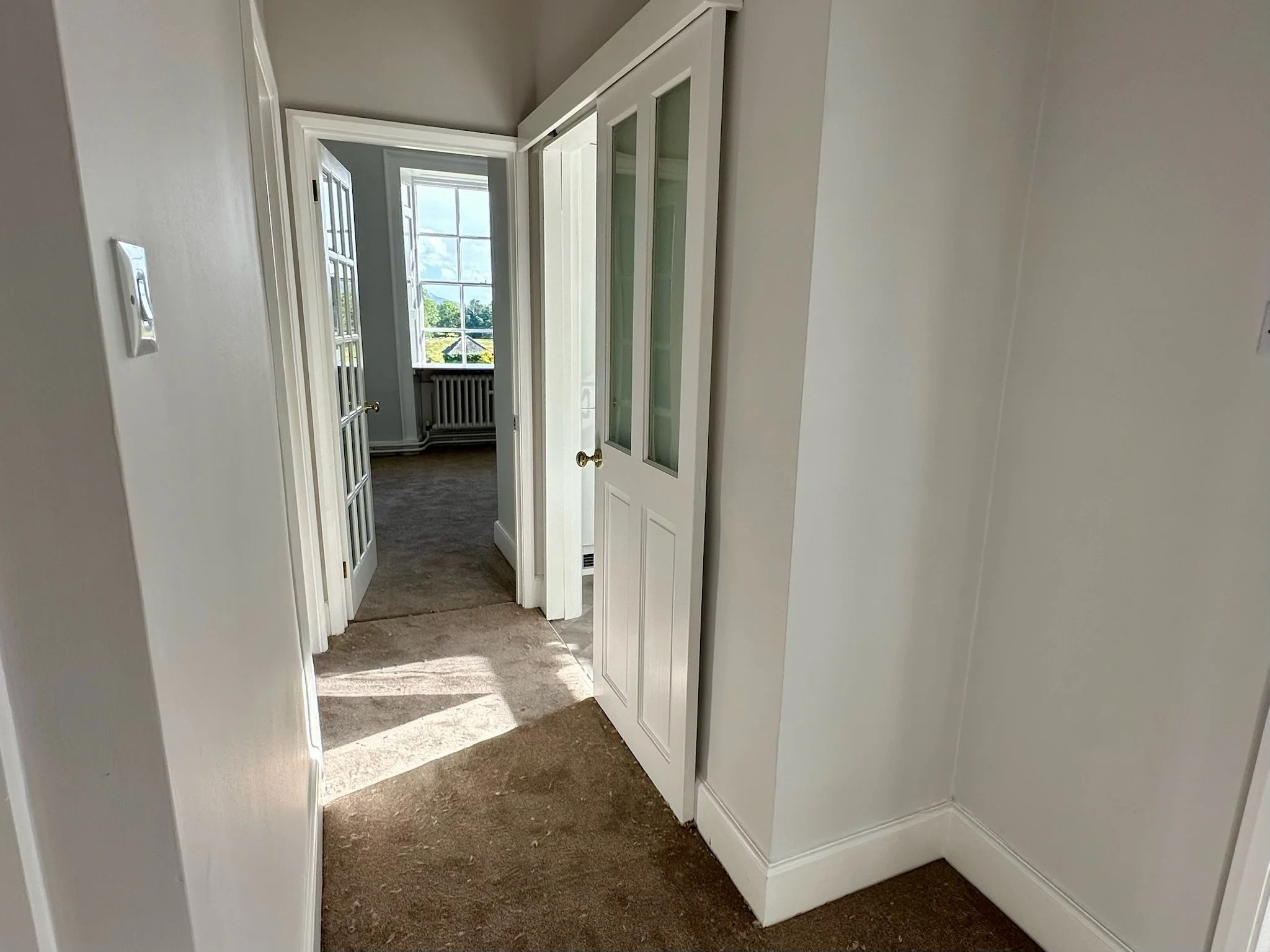 Spacious apartment hallway with period features and countryside views.