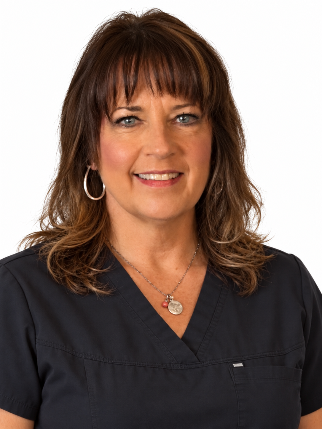 A woman with brown hair, blue eyes, and light makeup, wearing a black top or uniform, smiling slightly against a plain background.