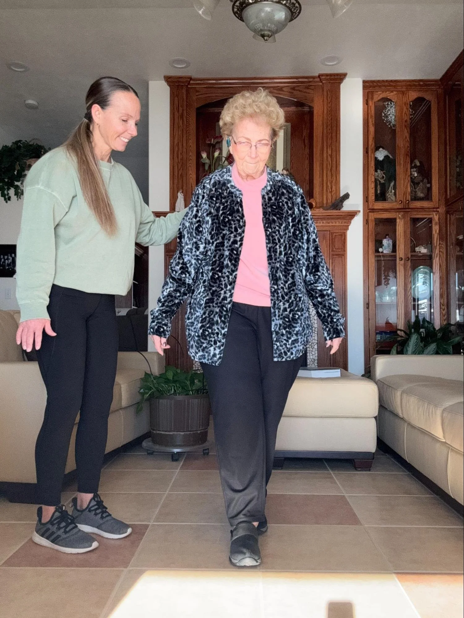 Kim of Prime BASE Fitness leads an elderly lady in an exercise in her home