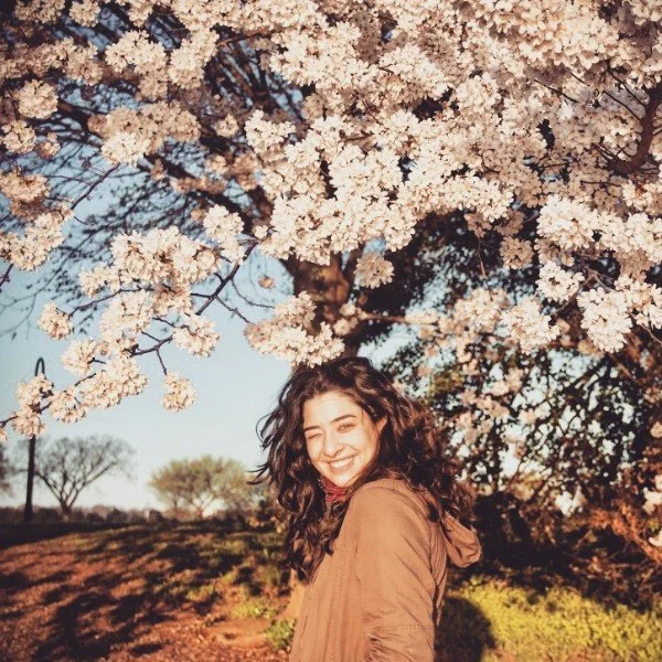 Emma smiling in front of a cherry tree.