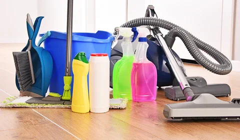 A collection of cleaning supplies and vacuum cleaners on a wooden floor.
