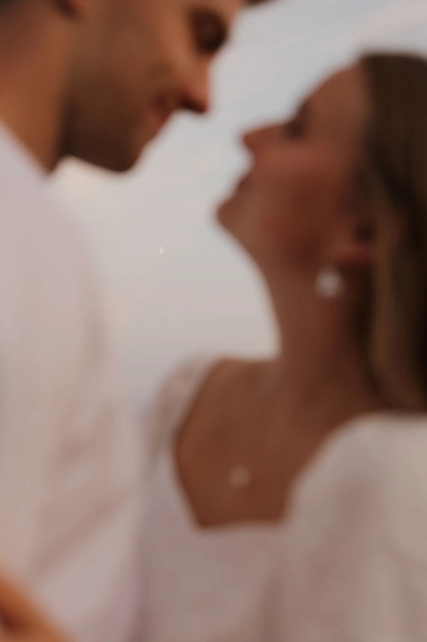 Close-up of a man and woman with their eyes closed, leaning towards each other as if about to kiss, with the background blurred.