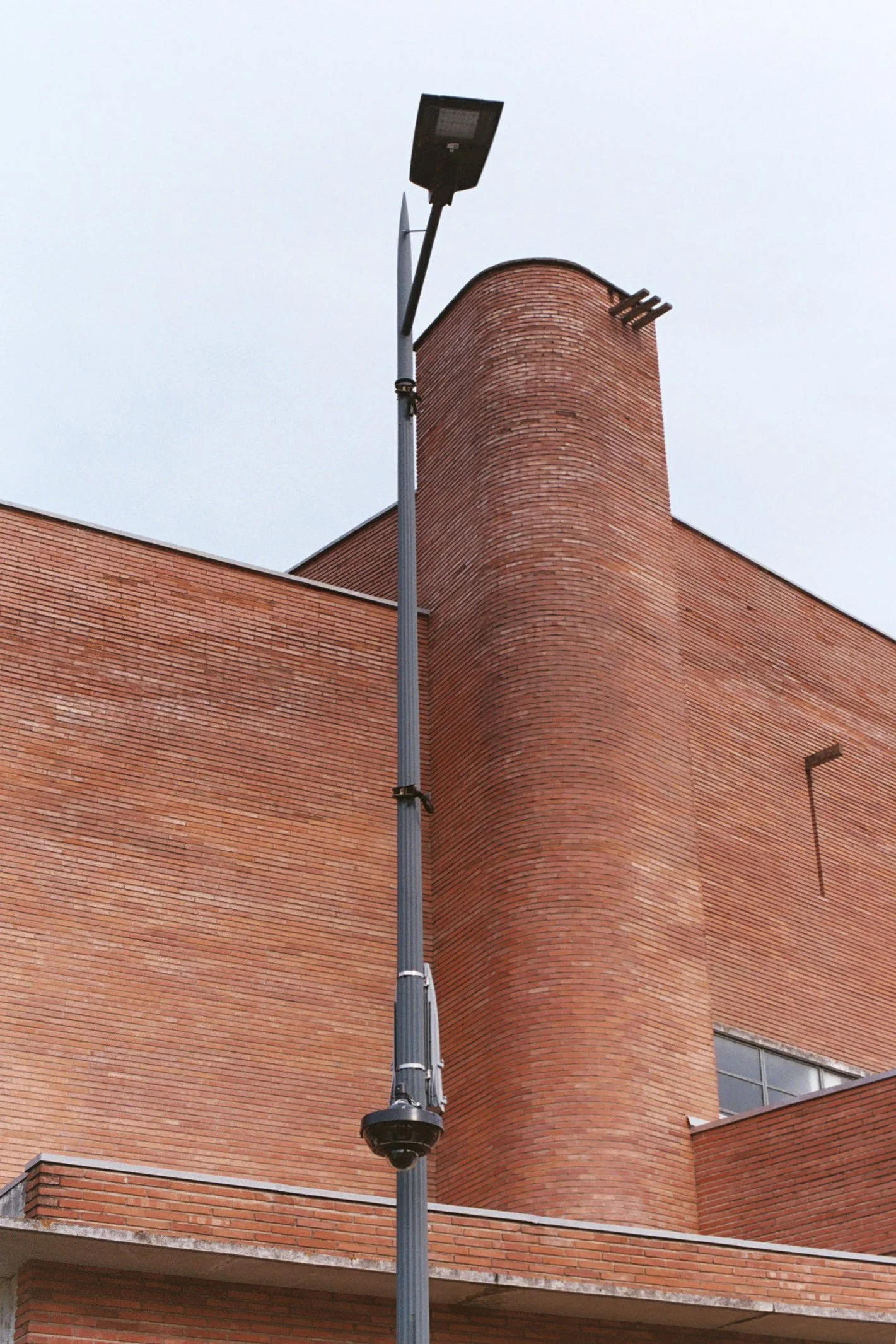 Lampe de rue installée devant un bâtiment en brique rouge avec une cheminée.