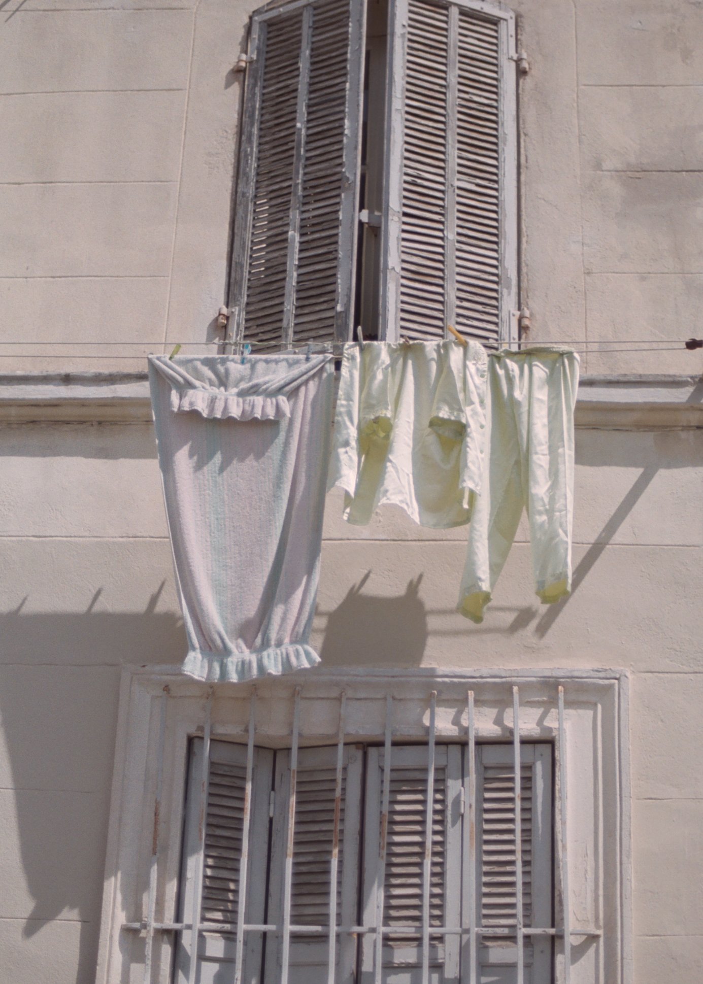 Fenêtre avec volets en bois et linge suspendu à une corde, sans personne visible.