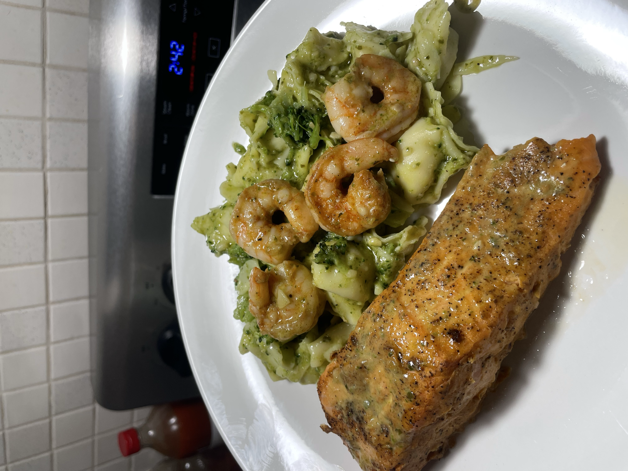 Pan-seared salmon with black pepper served with a side of pasta with shrimp, broccoli, and cheese