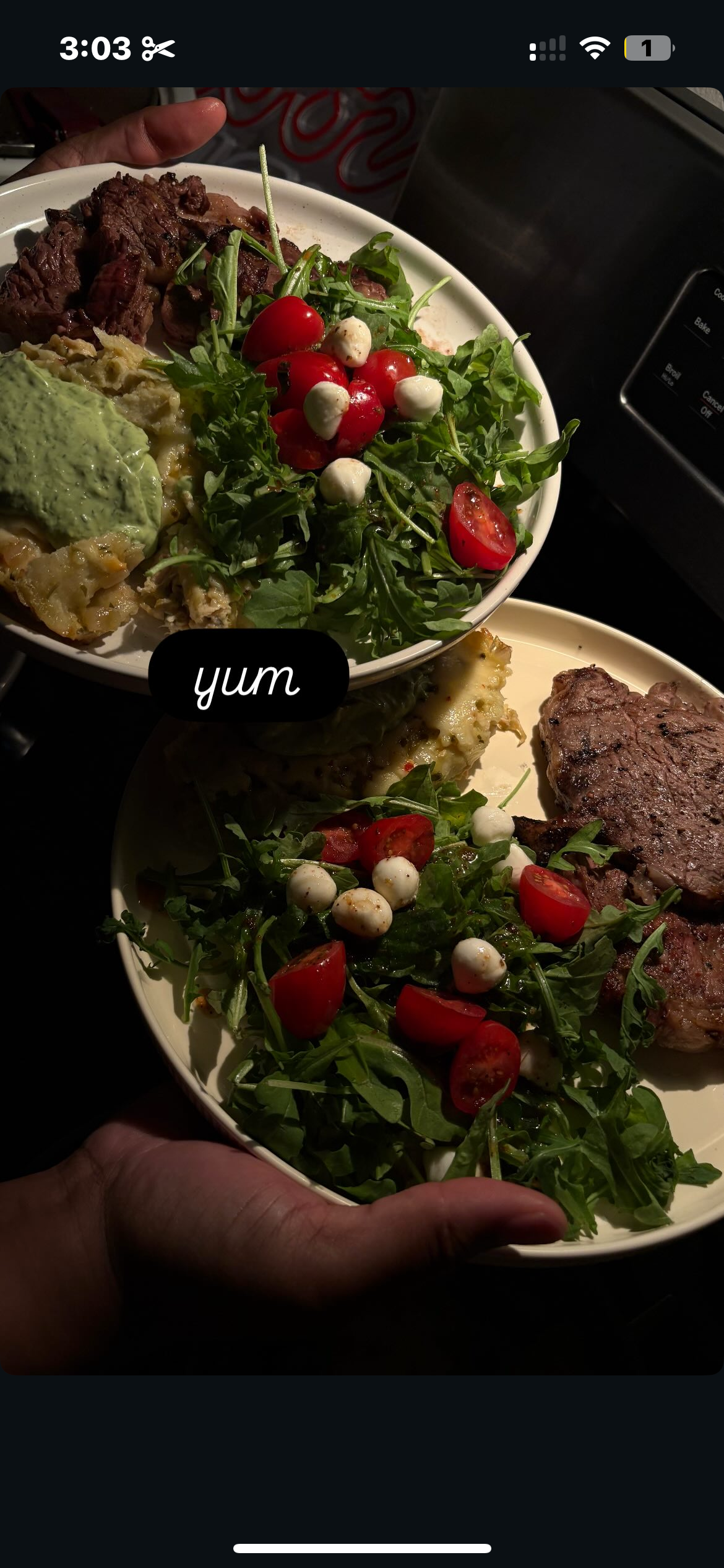 Two plates of food with salads containing cherry tomatoes, small mozzarella balls, arugula, and a baked dish topped with guacamole. One plate has a grilled steak.