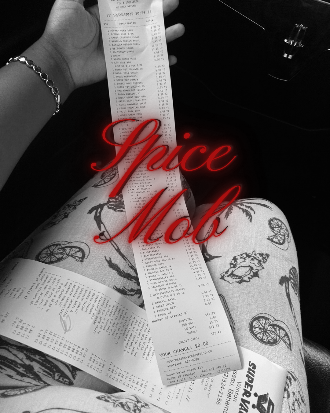 A person holding a long receipt with various food items and prices, sitting with crossed legs dressed in patterned pants, with the words "Spice Mob" written in red overlay on the image.