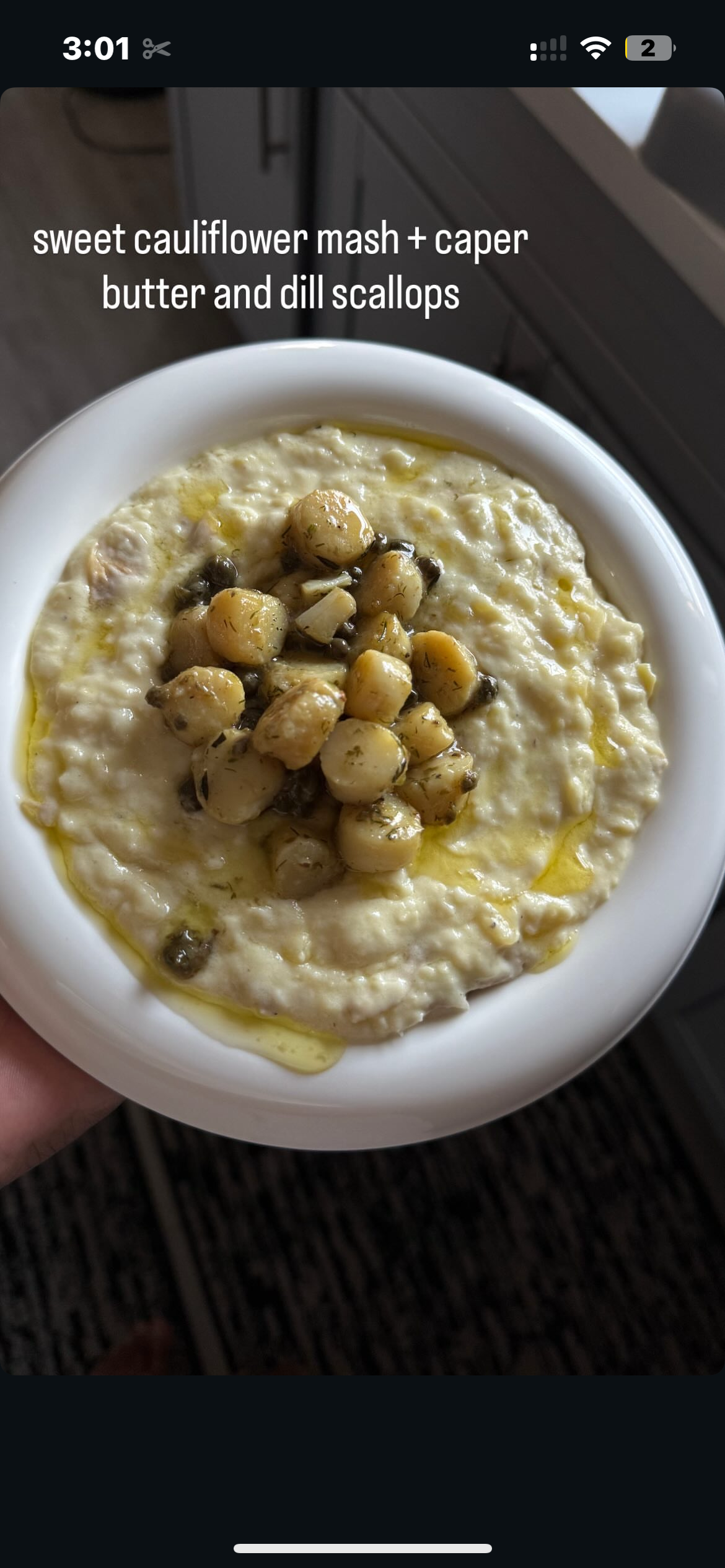 A bowl of sweet cauliflower mash topped with caper, butter, and dill scallops.
