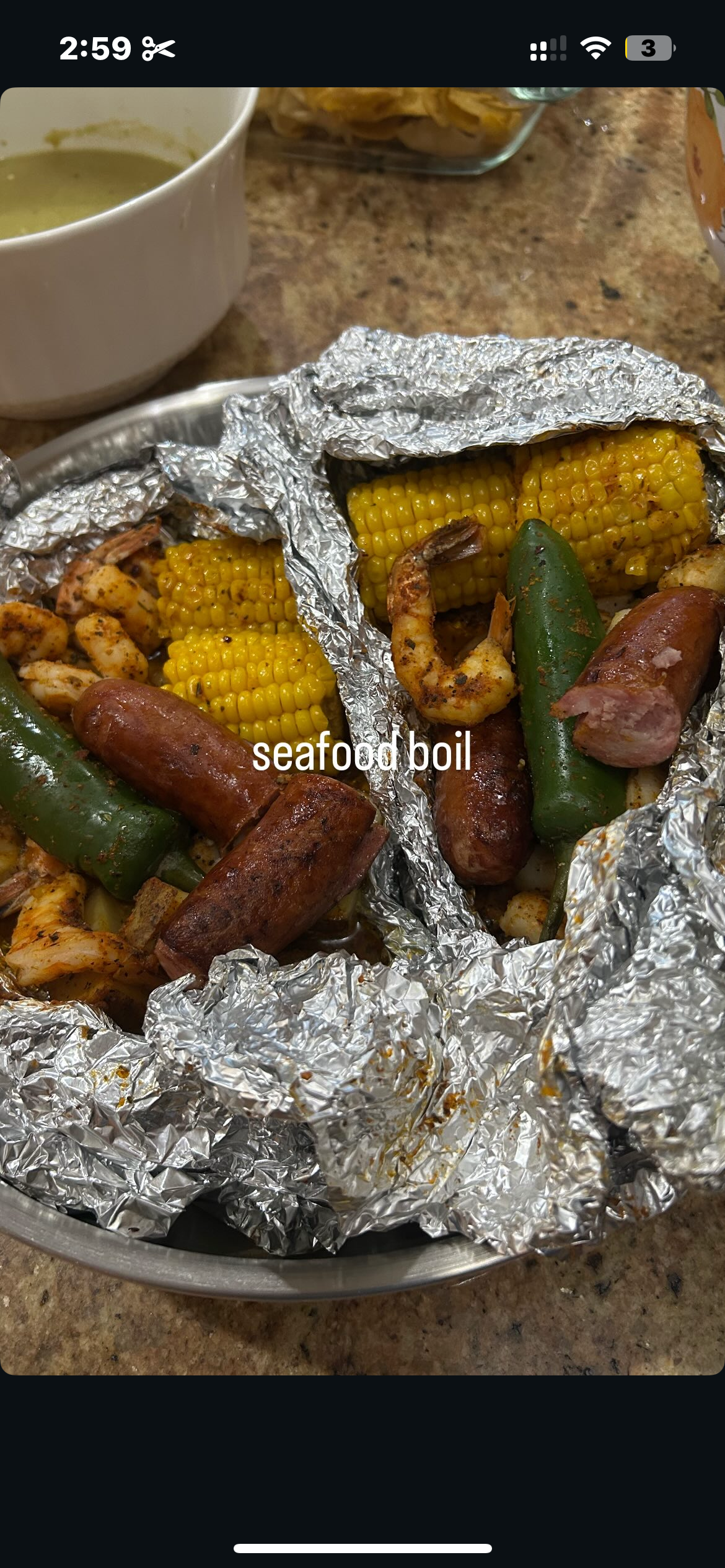 Foil-wrapped corn on the cob, sausage, jalapeño, shrimp, and chicken in a meal labeled 'seafood boil'